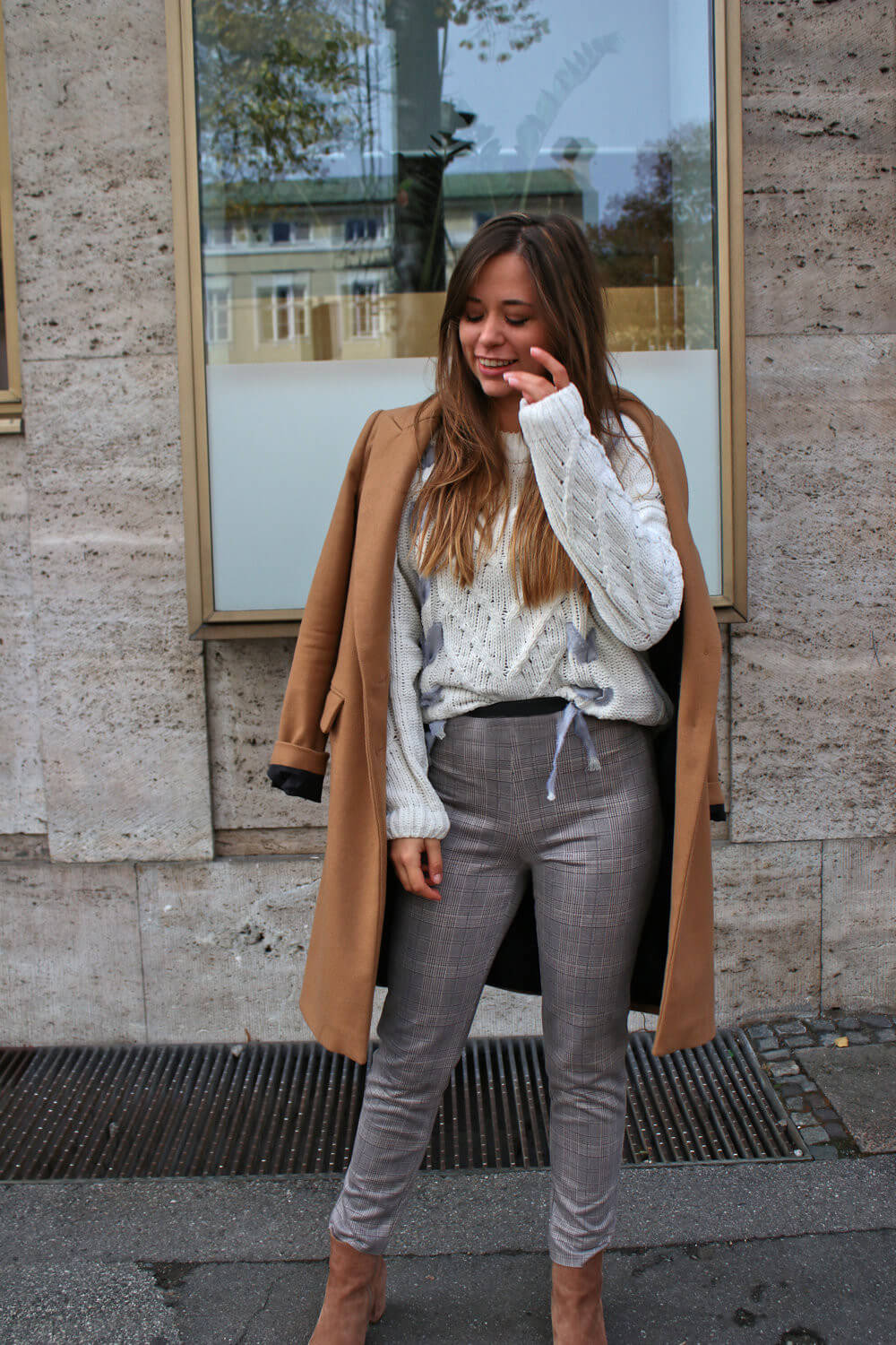 brauner Wollmantel weißer Strickpullover und Glencheck Hose