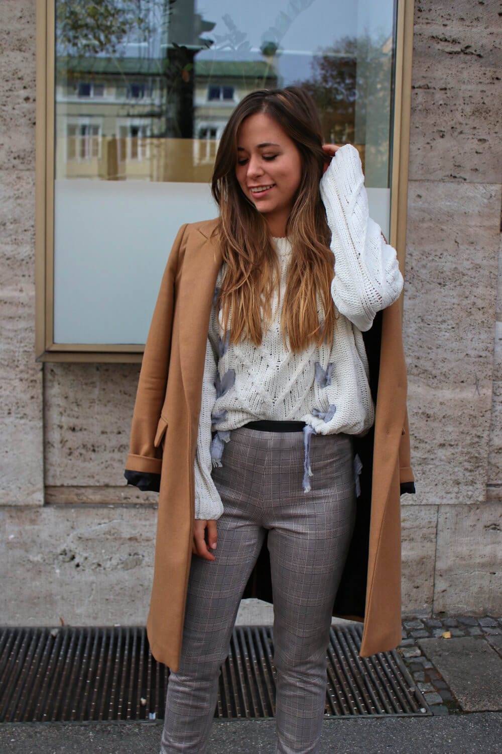 brauner Wollmantel weißer Strickpullover und Glencheck Hose